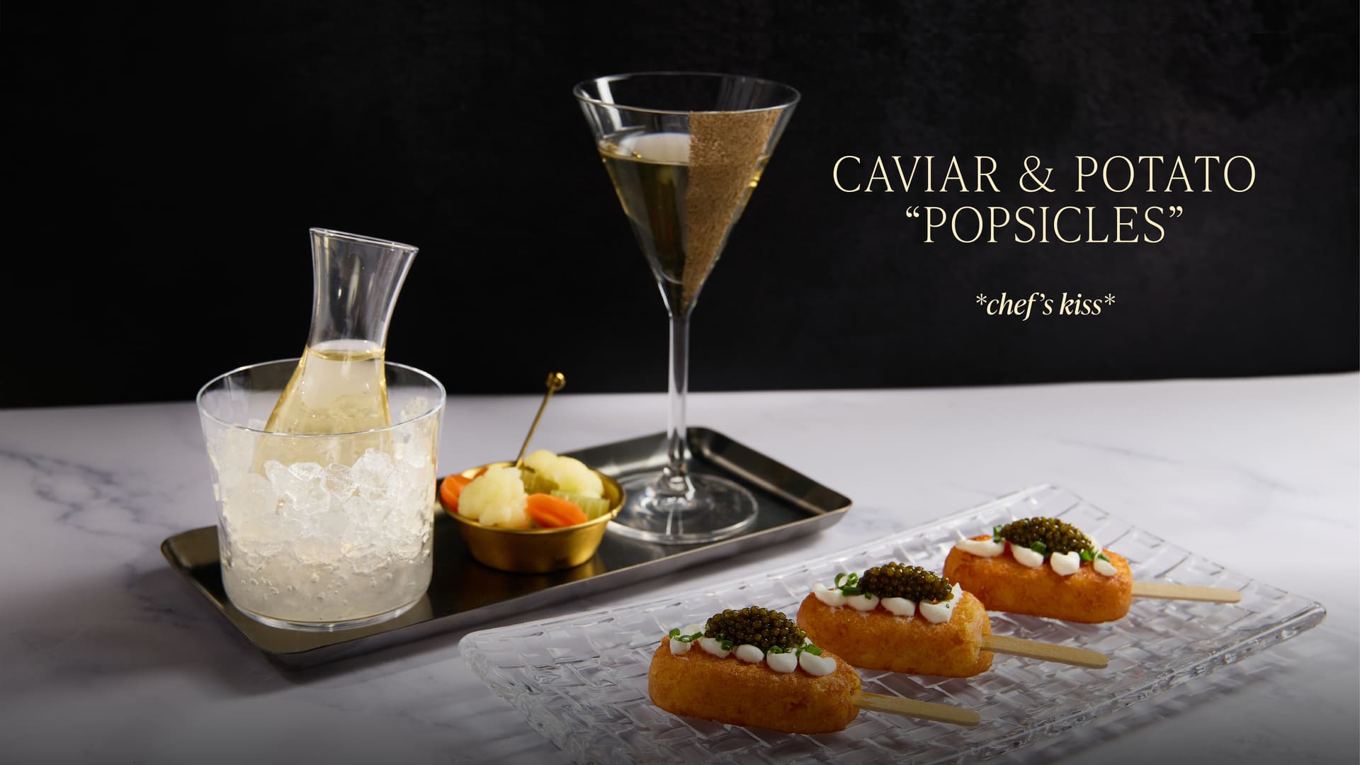 Caviar and potato bites served with martini and chilled carafe on a table
