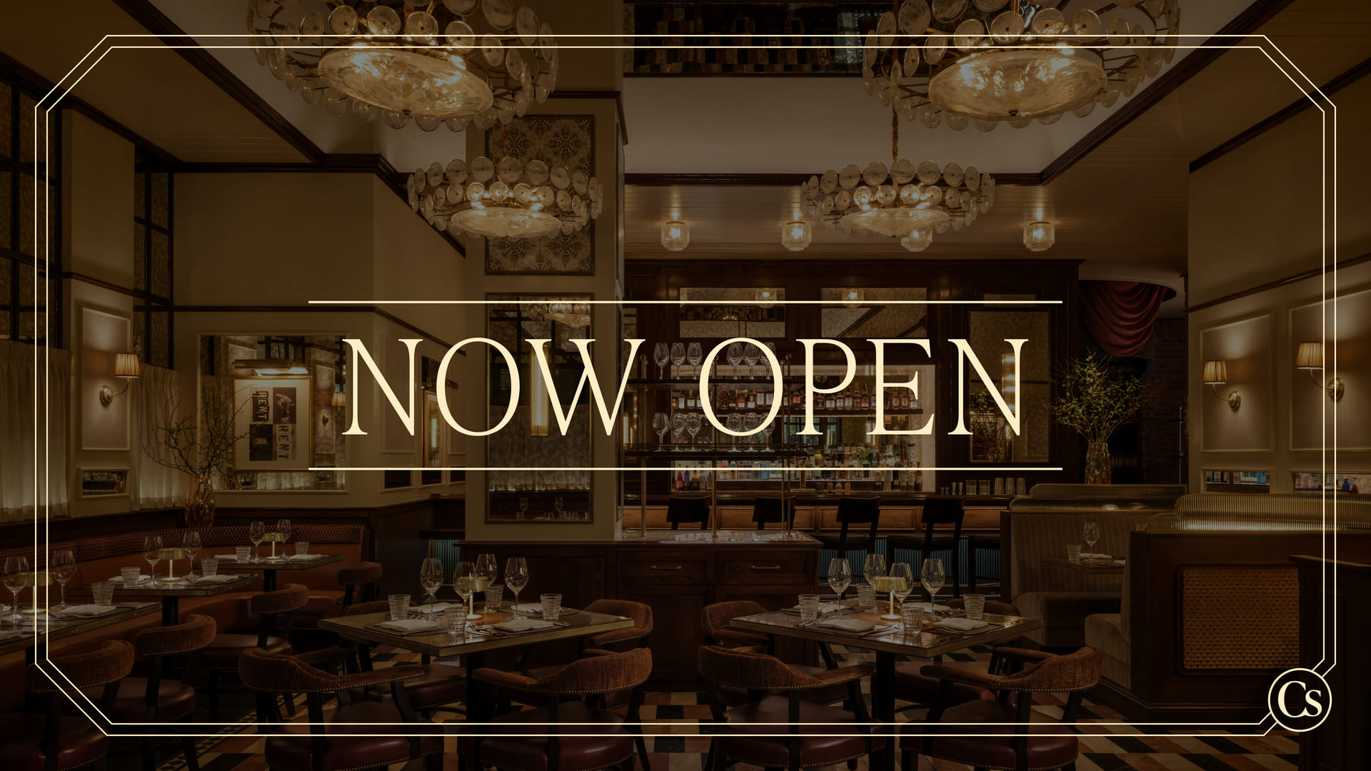 Restaurant interior with bar seating and chandeliers featuring “Now Open” text overlay