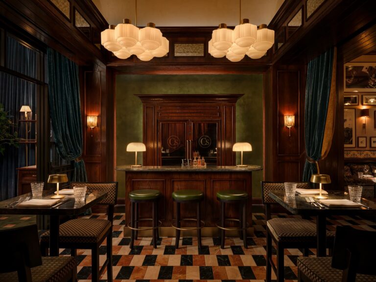 Classic steakhouse bar with wood paneling, green bar stools, and warm ambient lighting.