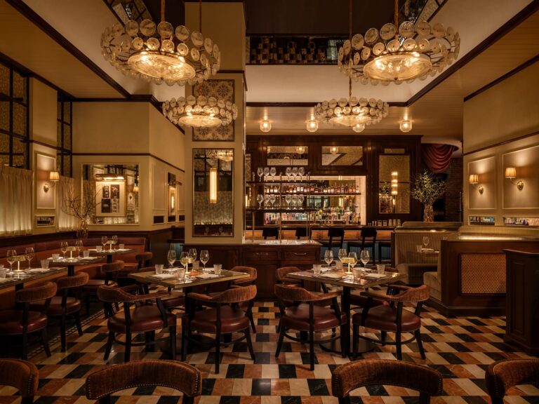 Elegant steakhouse dining room with chandeliers, marble tile floor, and warmly lit tables.