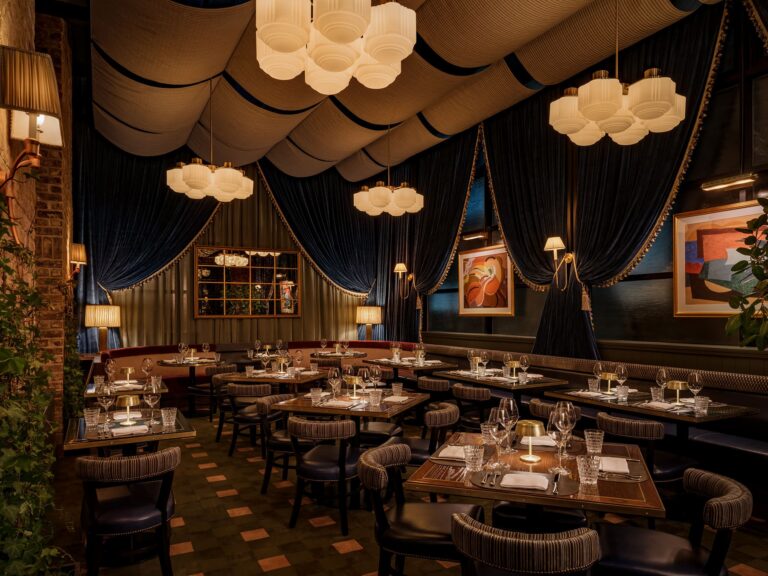 Upscale dining room with dramatic draped ceiling, chandeliers, and candlelit tables.