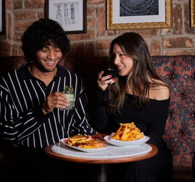 Couple enjoying drinks and burgers while seated at a restaurant table