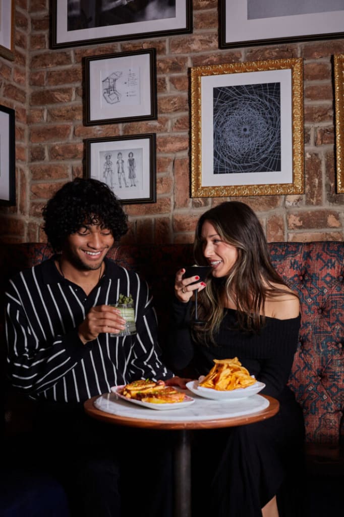 Couple enjoying drinks and burgers while seated at a restaurant table